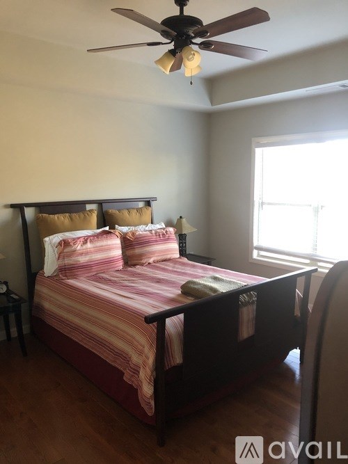 A bedroom with a bed, pillows, and a ceiling fan.