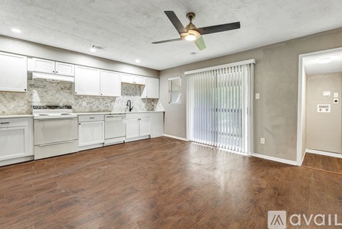 A spacious kitchen with white cabinets and a ceiling fan.