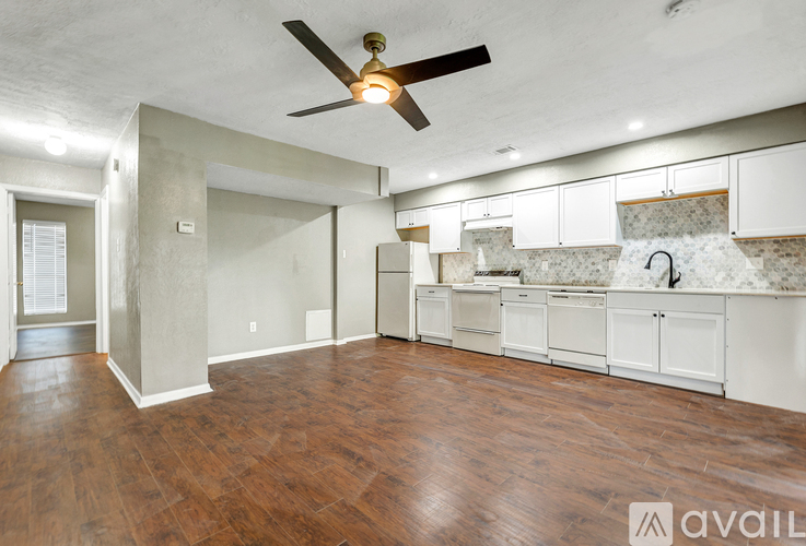 A spacious room with a ceiling fan and wooden flooring.