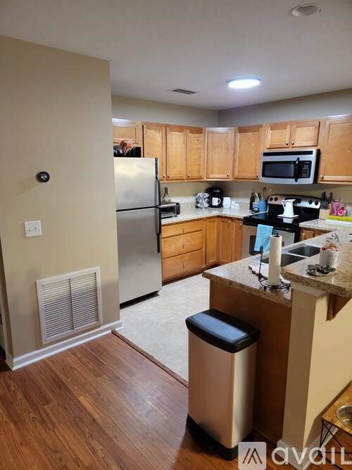 A kitchen with wooden cabinets and a stainless steel refrigerator.