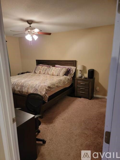 A bedroom with a bed, nightstand, and a ceiling fan.