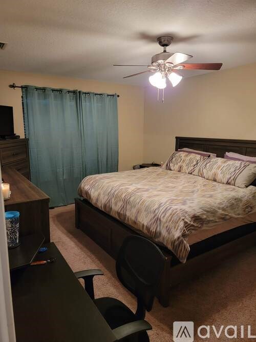 A bedroom with a bed, dresser, and ceiling fan.