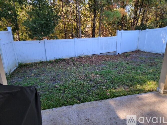 A backyard with a white fence and a black tarp on the ground.