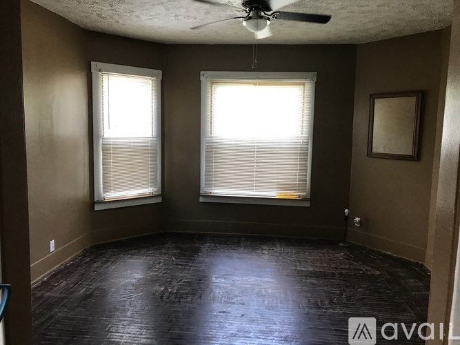 A room with a ceiling fan and two windows.