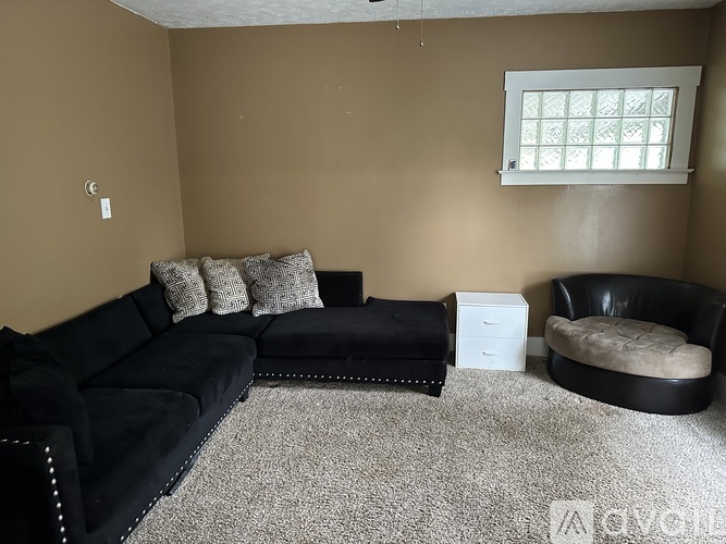 A living room with a black couch and ottoman.