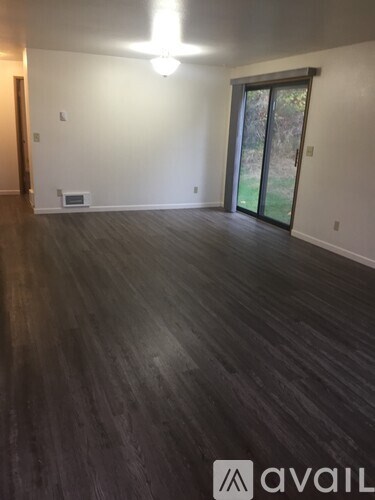 A room with wooden flooring and a sliding glass door.
