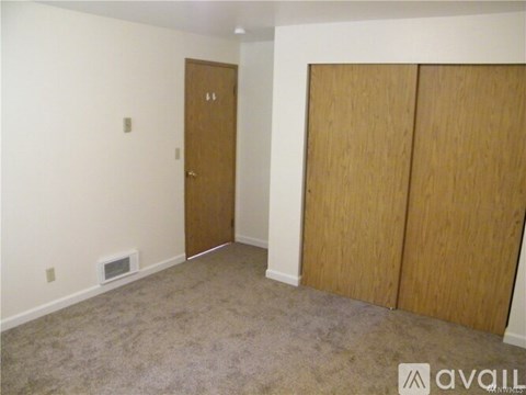 A room with a carpeted floor, a door, and a wall-mounted heater.