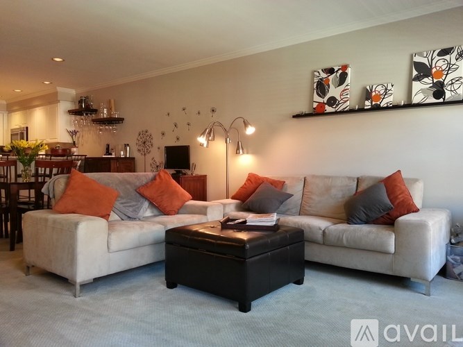 A living room with a white couch, a black coffee table, and a chandelier.