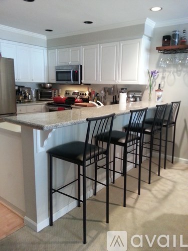 A kitchen with a bar area and four black chairs.
