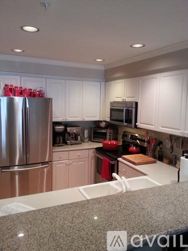 A kitchen with white cabinets and a stainless steel refrigerator.