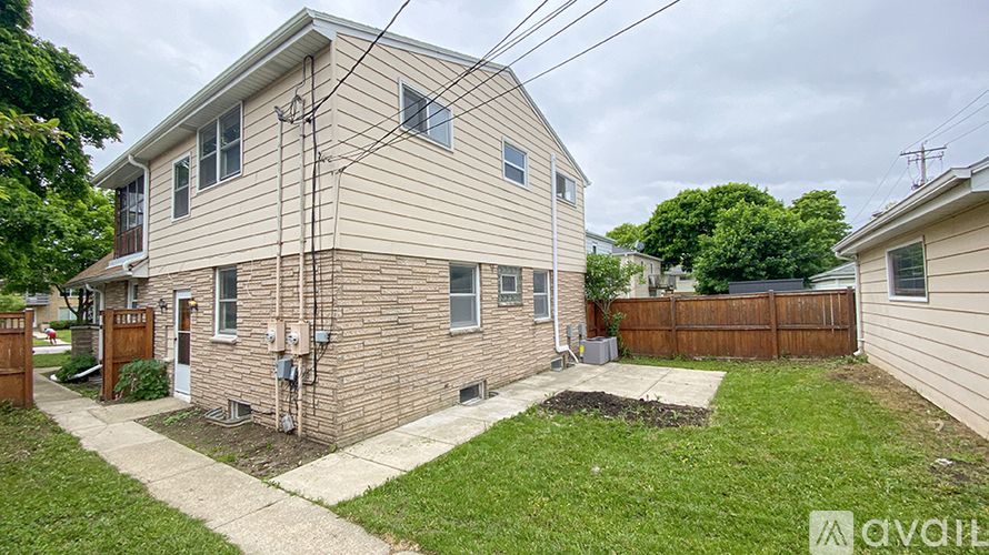A house with a beige siding and a brown fence is for sale.