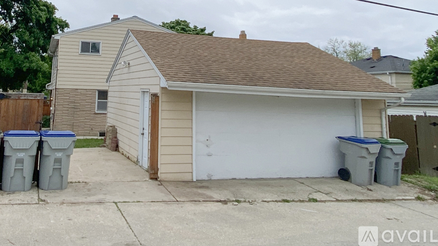 A house with a garage and three bins in front.