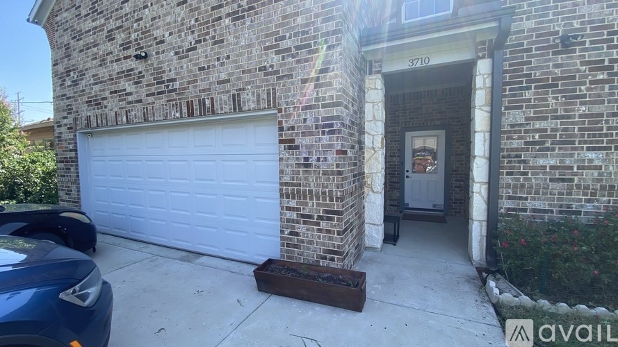 A house with a garage door and a sign that says "3710" on the wall.