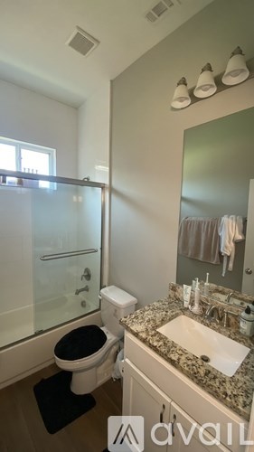 A bathroom with a toilet, sink, and mirror.