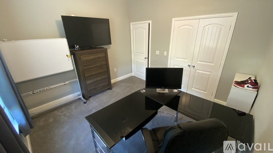 A black television sits on a black table in a room with white walls.