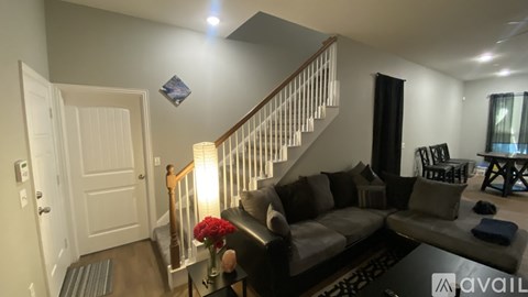 A living room with a grey couch and a staircase.