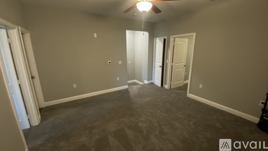 A room with a ceiling fan and a door on the right side.