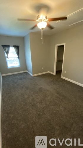 A room with a ceiling fan and carpeted floor.