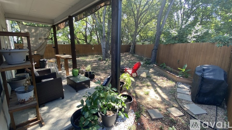 A patio with a table, chairs, and potted plants.