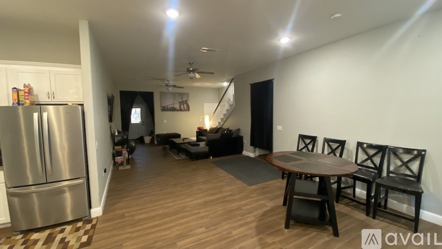 A kitchen with a refrigerator, a dining table with chairs, and a ceiling fan.