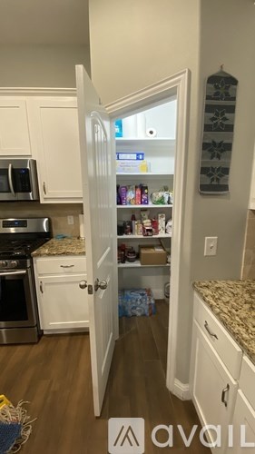 A kitchen with a refrigerator and a door open to a pantry.