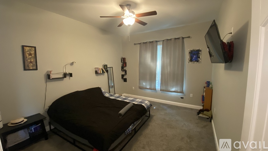A bedroom with a bed, a ceiling fan, and a window with curtains.