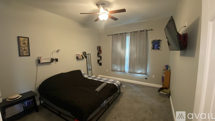 A bedroom with a bed, a ceiling fan, and a window with curtains.