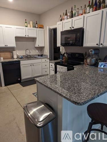 A kitchen with granite countertops and white cabinets.