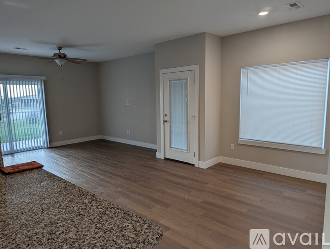 A room with a rug, a ceiling fan, and a door.