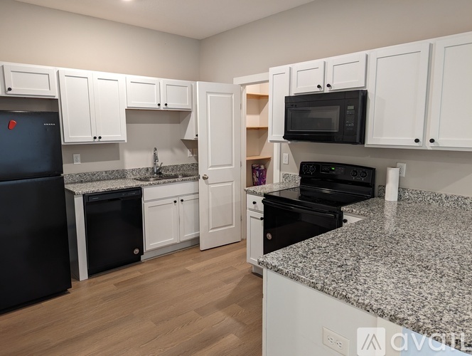 A kitchen with white cabinets and black appliances.