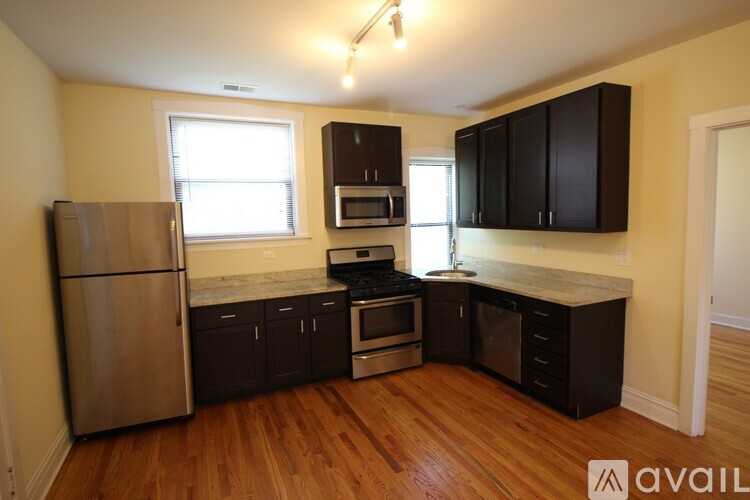 A kitchen with wooden floors and a stainless steel refrigerator.