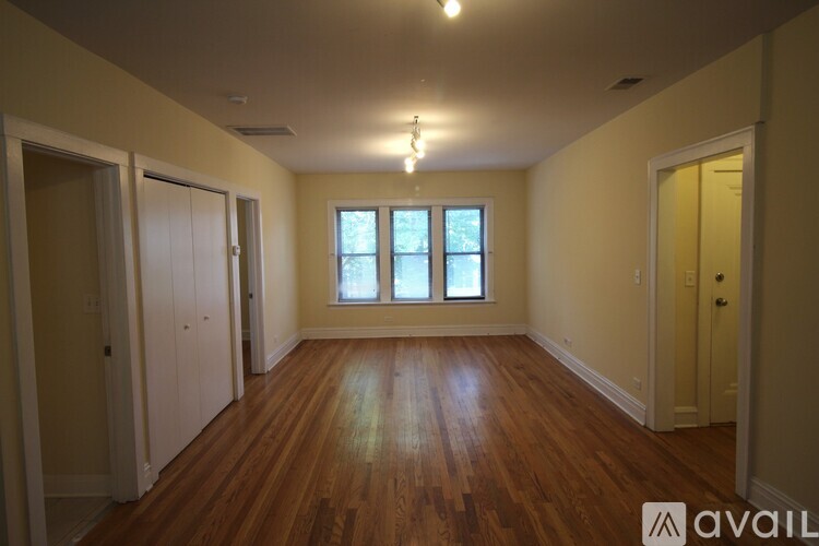 A room with wooden floors and a window with white curtains.
