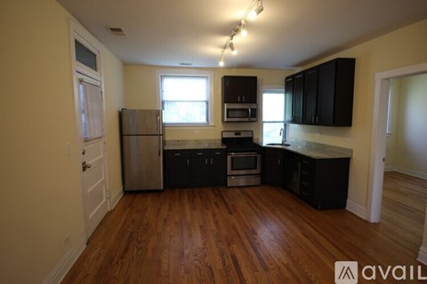 A kitchen with black cabinets and a wooden floor.