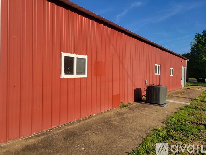 A red building with a white window and a grey air conditioning unit.