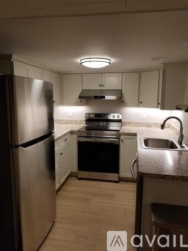 A kitchen with a refrigerator, oven, and sink.