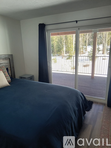 A bedroom with a large bed and a view of a snowy landscape outside the window.