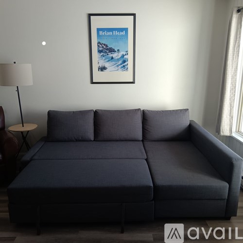 A grey sofa with a framed picture of a beach scene by Brian Head is in the foreground.
