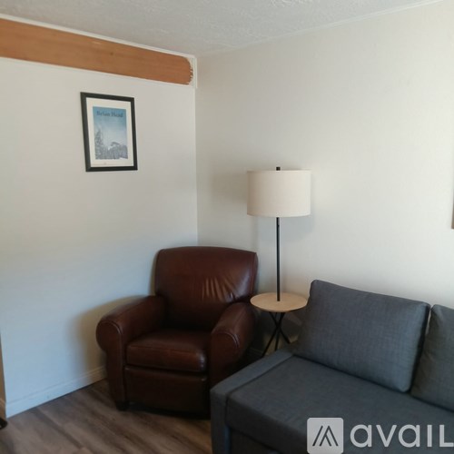 A brown leather chair sits next to a grey couch in a room.