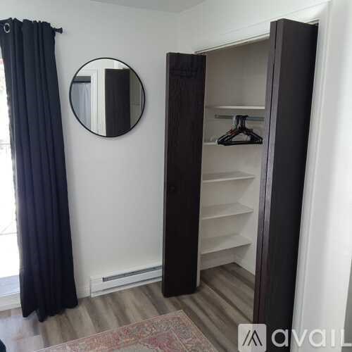 A black wardrobe with a mirror above it and a black curtain to the left.