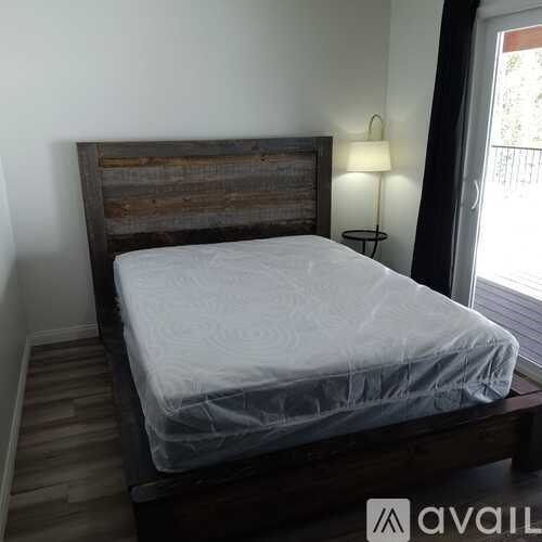 A bed with a wooden headboard and a white sheet is in the image.