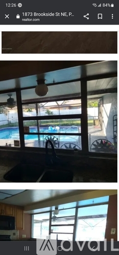 A view from inside a room looking out through a window at a pool and a fence.