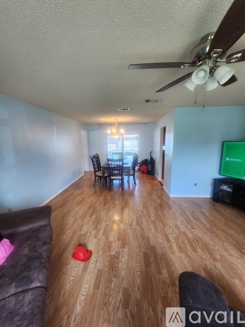 A living room with a brown couch and a ceiling fan.