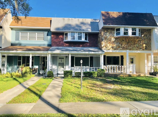 A house with a white front porch and a stone wall on the side.