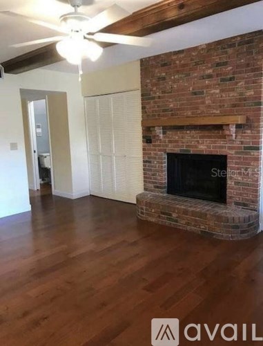 A room with a brick fireplace and wooden floors.