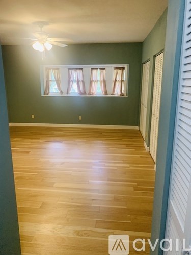 A room with wooden flooring and a window with curtains.
