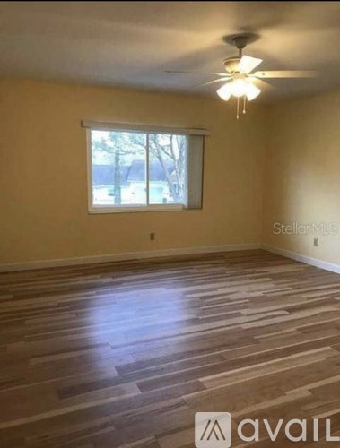 A room with wooden flooring and a ceiling fan.