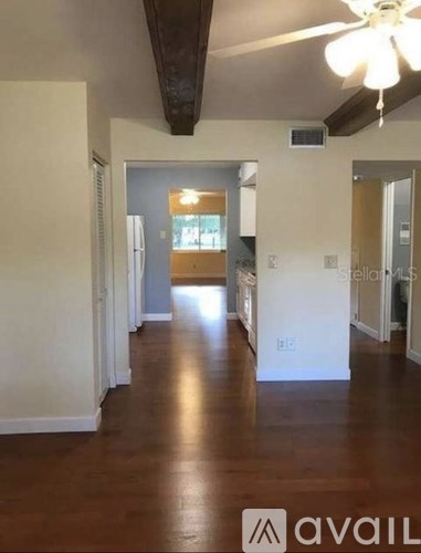 A long hallway with a fan and wood floors.