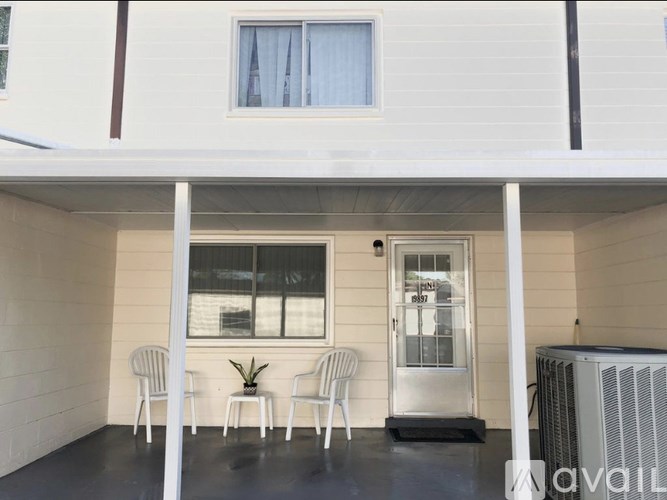 A white house with a balcony has a sign on the door.