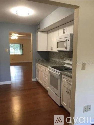 A kitchen with white cabinets and a black countertop.