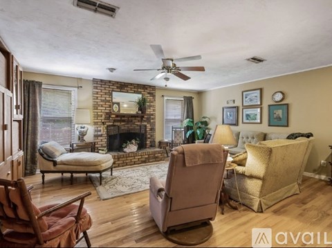 A living room with a fireplace, two chairs, and a couch.